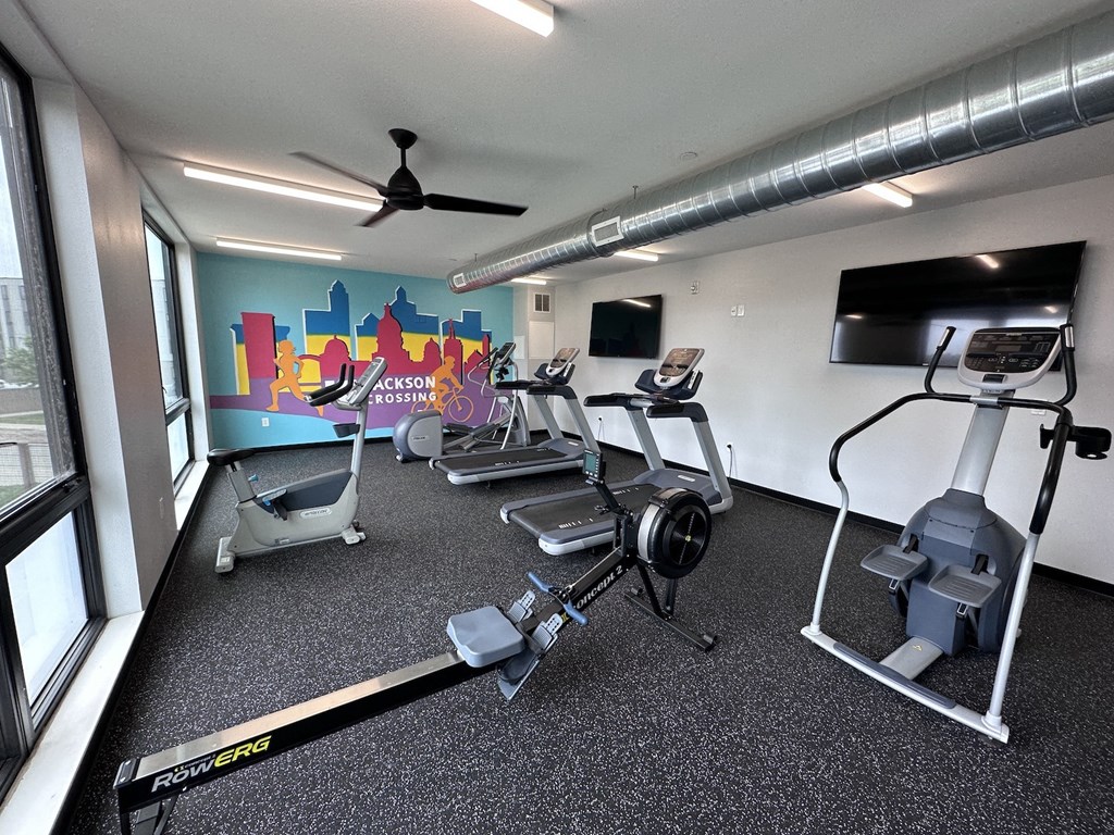 a gym with exercise equipment and a wall mural